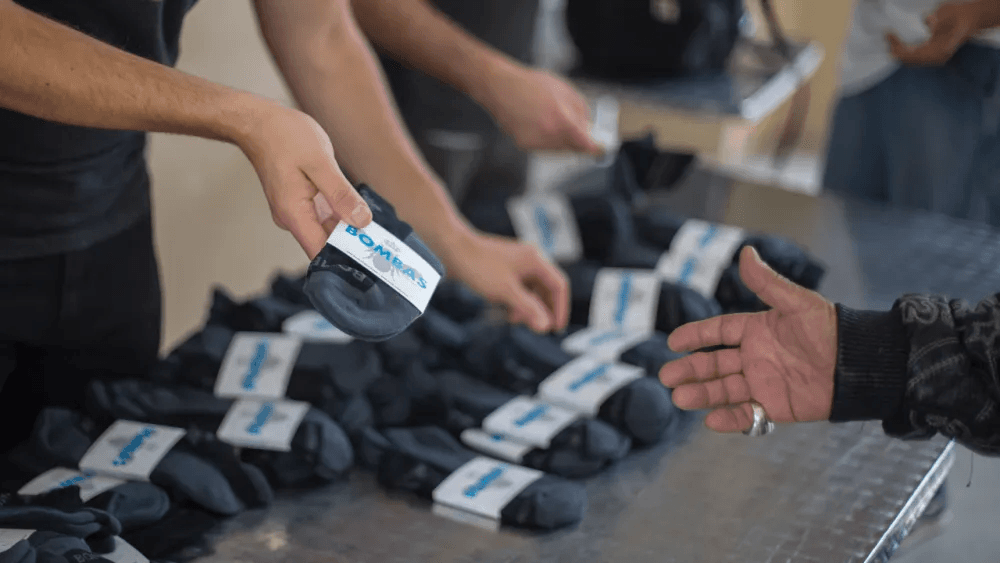Volunteers handing out Bombas socks at a donation table